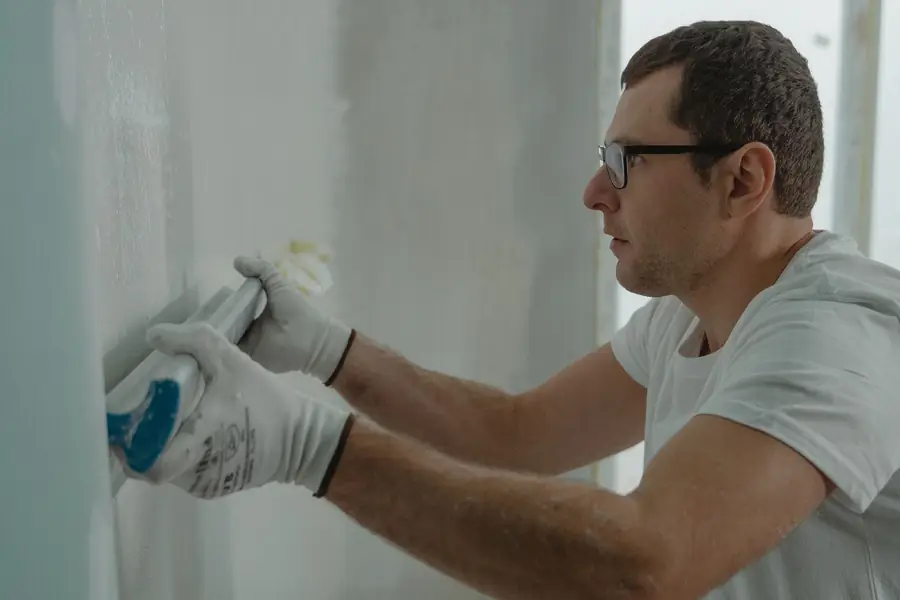 Drywall finisher smoothing joint compound on a wall before painting