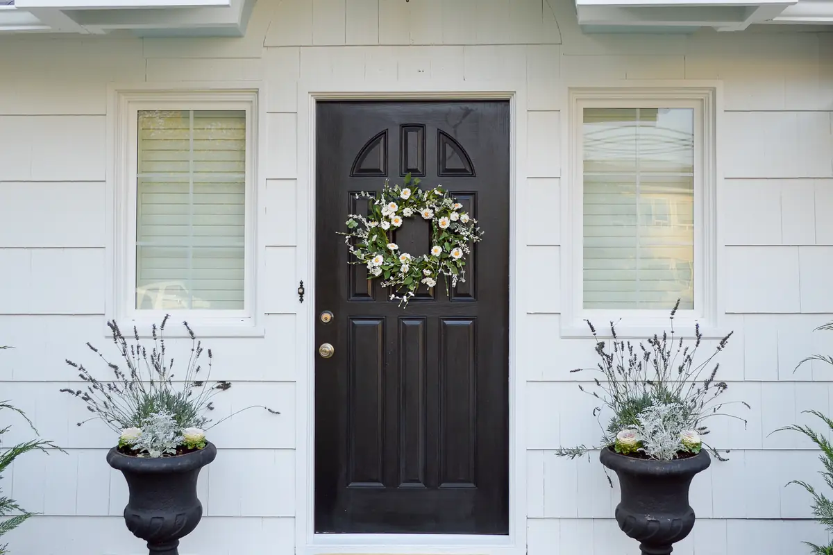 Front entry with white siding, an arched portico and a black front door after painting